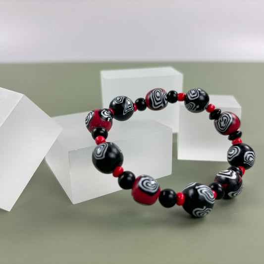 Mystic Swirl – Handgefertigtes Perlenarmband in Schwarz-Rot mit einzigartigem Spiralmuster